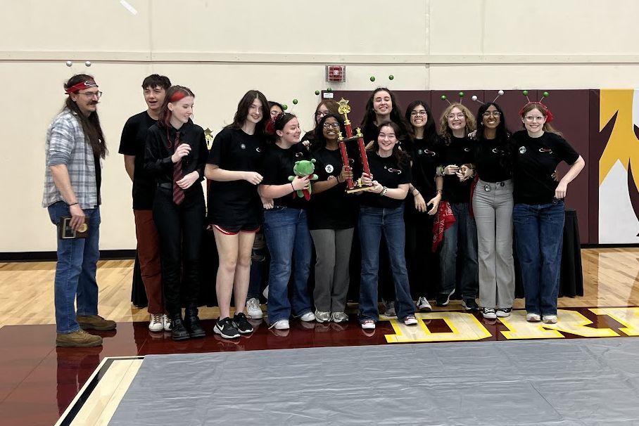 The team celebrating with a trophy on the gym floor